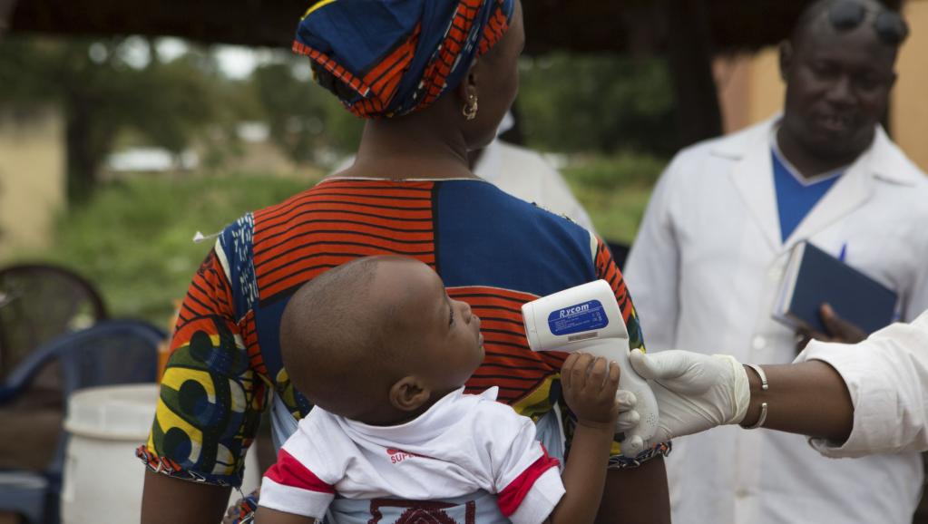 Un personnel de santé contrôle la température d'un bébé à la frontière entre la Guinée et le Mali, le 2 octobre 2014.