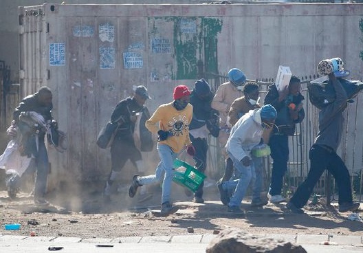 Des pilleurs en portant des objets volés en Afrique du Sud