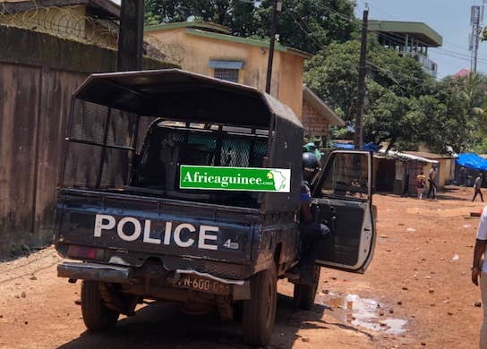 Feature image Un véhicule de la police face à des manifestants à Bambéto