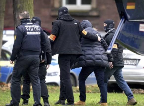 Un suspect escorté par la police arrivé à Karlruhe le 7 décembre. Des milliers de policiers ont effectué plusieurs arrestations en Allemagne, en Autriche et en Italie arrêtant des membres d'une organisation d'extrême droite soupçonnés de vouloir prendre d'assaut le parlement allemand, crédit photo AFP