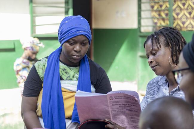 Fatoumata, explique à cette maman l’importance de suivre le calendrier vaccinal de son enfant. Centre de santé de Tombolia, Conakry Guinée.