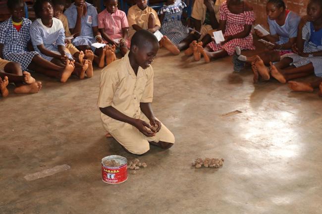 Un élève de l'école primaire Général Lansana Conté de Dubréka en train de faire des calculs à l'aide des pierres.